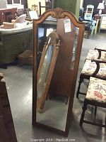 Full view of the carved wood floor mirror showing height, shape, and placement in room.