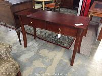 Photo of wooden foyer table from an angle showing two drawers and one floral handle.