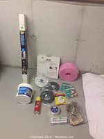 Photo showing various construction and sealing materials including vapor barrier roll, melamine edging, foam strips, tapes, sealant, and gloves