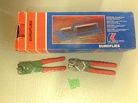 Two tile nippers, one green-handled and one metallic, placed in front of a Euroflies tile cutter box