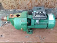 Side view of green metal body Myers jet pump with black motor housing showing wear and rust spots.