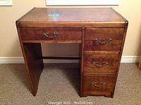 Full view of vintage wood desk showing front with four drawers and slightly rounded edges.