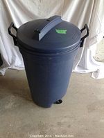Front-side view of the Rubbermaid Roughneck garbage can showing the lid with handle and side handles.