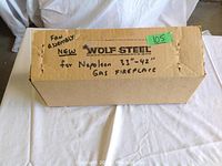 Closed cardboard box labeled 'Wolf Steel fan assembly for Napoleon 33"-42" gas fireplace'
