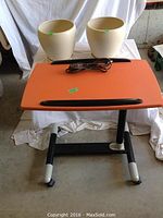 Work table with orange top, two beige clay flower pots, and brown extension cord displayed on table
