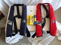 Two vests (blue and red) and yellow rearm kit packaging laid flat