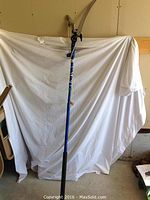 Full view of the blue tree pruner with collapsed white sheet backdrop showing the length and handle grip.