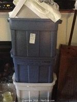Three plastic totes stacked, two blue and one white, containing various items.