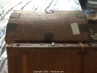 Wooden vintage trunk with lid removed, showing metal corner reinforcements and aged leather straps.