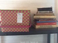 Photo of the cookbooks stacked with multiple titles visible, alongside two multicolored woven storage baskets.