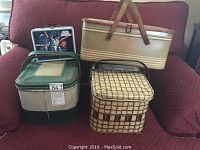 Three vintage metal picnic baskets arranged on a chair, including the Star Wars lunch box placed on top of the green/white basket.