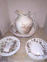 Set of 7 brown and white transferware ceramic pieces including large wash basin, pitcher, two plates, and three bowls shown together.