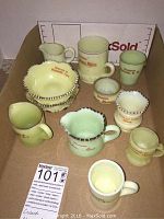 Full view of eleven custard glass souvenir items, including pitchers, mugs, and bowls from New England towns and cities.