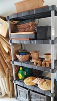 Full view of Rubbermaid plastic shelving loaded with assorted garden pots of various sizes and garden decorations. Includes plant food.