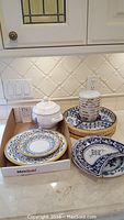Photo of Cama Deruta serving plates, white sugar bowl and Chinese bowls stacked in a basket