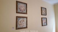 Wall display of four square framed floral pictures arranged in two rows of two.