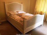 Assembled queen size bed in white frame with bedding