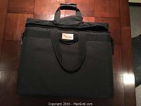 Front view of the black iMac carrying case showing handles and external pockets.