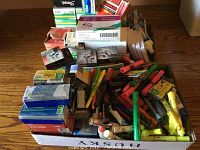 Top view of assorted office supplies showing markers, highlighters, envelopes, staples, and clips stacked in boxes.