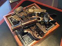 Brass sextant resting in open wooden hinged box with felt interior