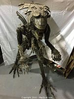 Frontal view of full sculpture in crouched stance showing head crest, open mouth and extended arms