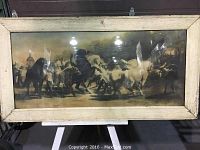 Framed wide artwork showing group of horses and people inside a wooden distressed frame with glass front