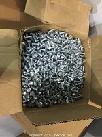 Open cardboard box filled with numerous shiny 1 inch pan head bolts with coarse threading, showing quantity and packaging.
