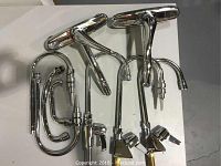 Two American Standard single lever faucets and three Delta cold water only single lever faucets with handles on white surface.