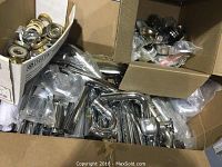 Photo of box containing many shiny chrome curved plumbing pipes in various sizes.