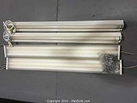 Four 48-inch fluorescent light fixtures laid on floor, showing the general size and condition, with power cords visible.