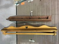 Two wooden pine wall shelves stacked; top shelf is darker stained with plate rail and pegs, bottom shelf is lighter with blanket bar and heart cut-out.
