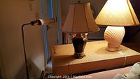 Table lamps and floor lamp grouped together on a surface, showing ceramic bases and lamp shades