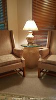 Occasional table positioned between two armchairs with a lamp on top, showing overall setup and size.