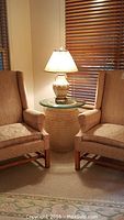 Full shot of the table lamp placed between two armchairs, showing its size and setting.