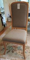 Front-facing view of one upholstered dining chair showing the curved legs and fabric upholstery.