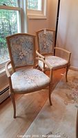 Pair of dining room armchairs positioned near window showing wood and upholstery details