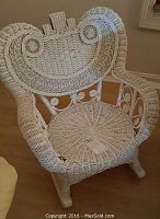 White wicker child's rocking chair with detailed woven swirl patterns visible on the backrest and seat.