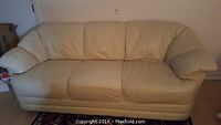 Front view of the cream leather sofa showing overall condition.