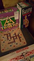 Photo showing TriBond, Bandu, Spinning Scrabble game board, and part of Monopoly box.