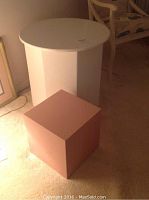 White round wooden table and a smaller cube-shaped wooden item beside it.