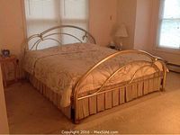 Full view of the king-size brass bed frame with Sleep Number mattress and bedding in a beige-toned bedroom.