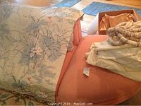 Full drape set including floral and ivory drapes, folded and packed on a pink chair showing additional fabric pieces.