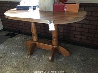 Full view of the round kitchen table with wooden pedestal base and Formica top displaying overall condition and structure