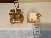 Metal chalice set and costume jewelry displayed on a table with a MaxSold tag