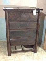Front view of wooden chest with four drawers, bottom drawer missing.