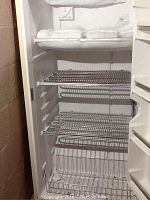 Interior of the freezer showing three wire shelves and frost build-up on the top shelf.
