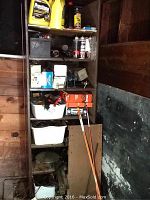 Photo showing shelves with automotive fluids, tools, and parts including cans of Prestone, fluid bottles, and boxed parts on wooden shelves.