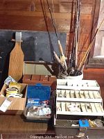 Various fishing tackle in two plastic tackle boxes without handles placed on wooden floor, showing fishing line, lures, and hooks