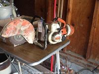 Full view of the Stihl concrete saw on a wooden table, showing motor and blade assembly.
