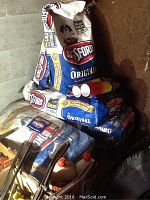 Five 20-lb bags of Kingsford Original charcoal stacked, two opened, with Flame Stop cans and lighter fluid alongside.